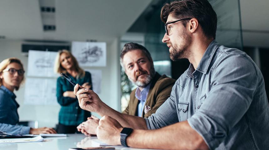 Young designer giving some new ideas about project to his partners in conference room. Business people discussing over new business project in office.